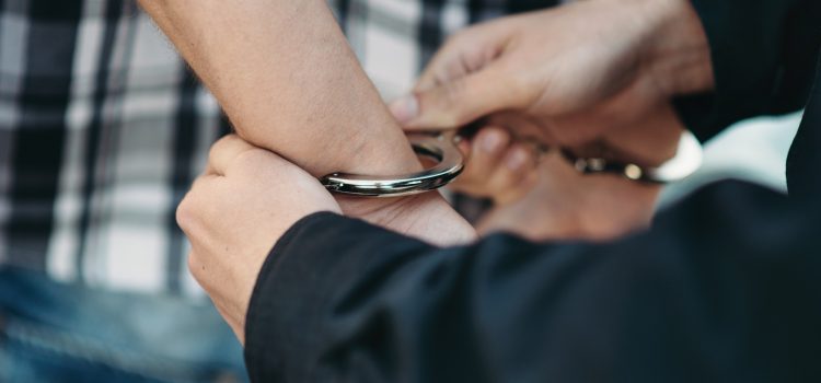 Police officer puts handcuffs on a car thief, policeman arrests the driver violator on road. Cop at the work. Law protection concept, professional safety control